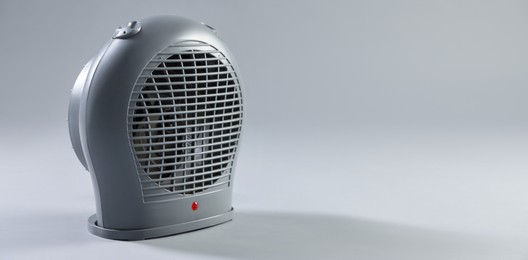 Photo of Modern electric fan heater on light grey background, space for text