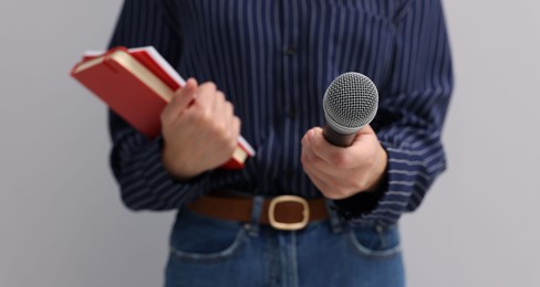 Photo of Journalist with microphone and notebooks on light background, closeup
