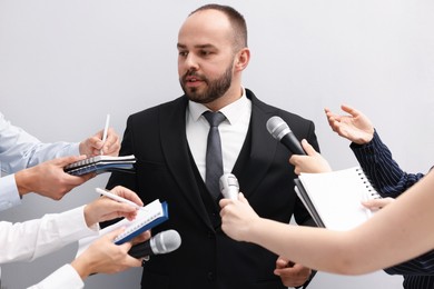 Photo of Businessman giving interview to journalists on light background