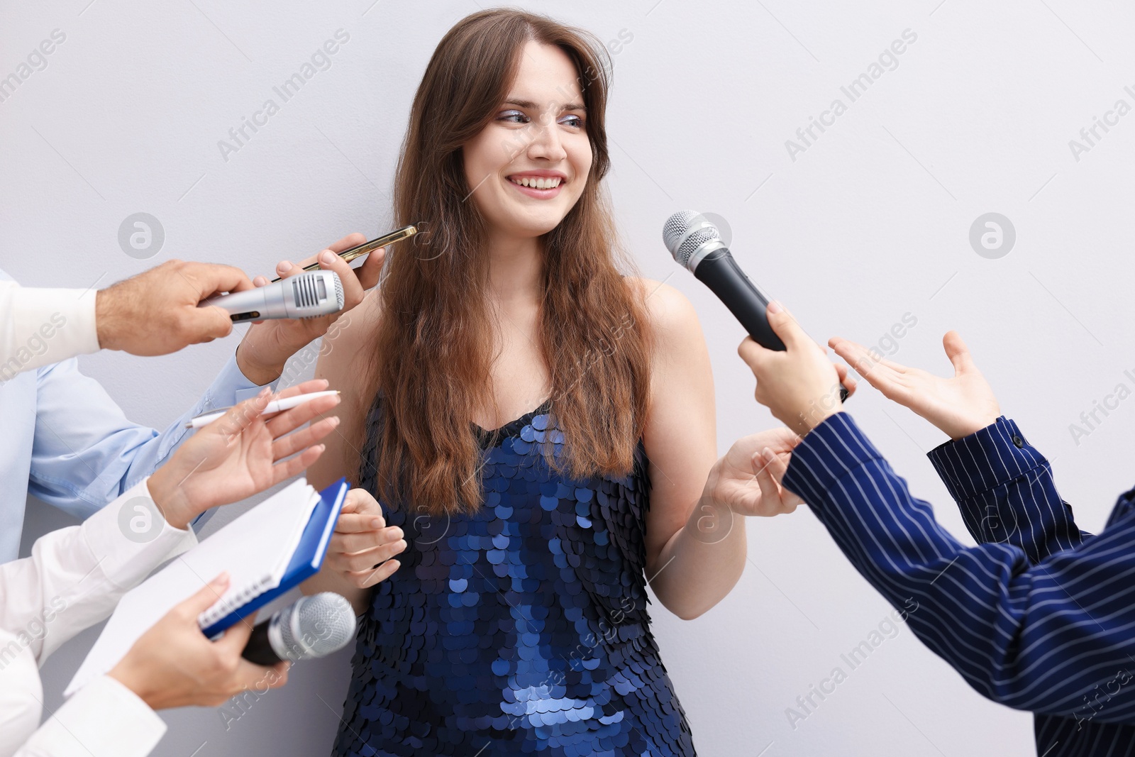 Photo of Beautiful woman giving interview to journalists on light background