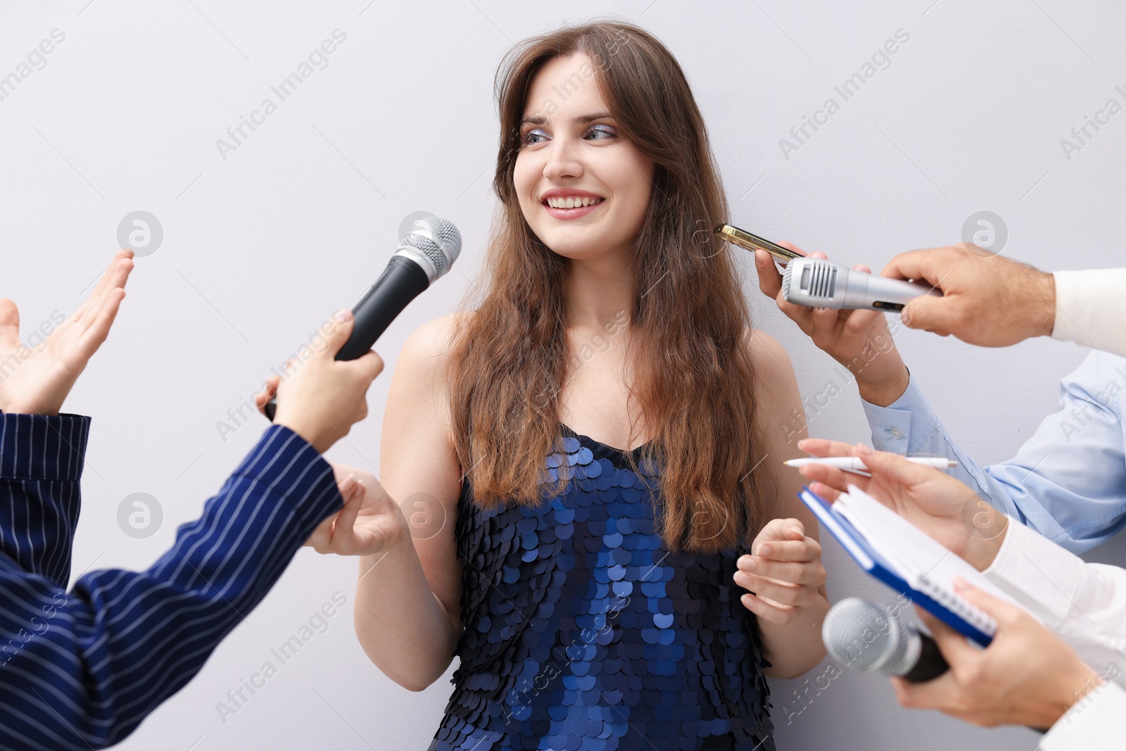 Photo of Beautiful woman giving interview to journalists on light background