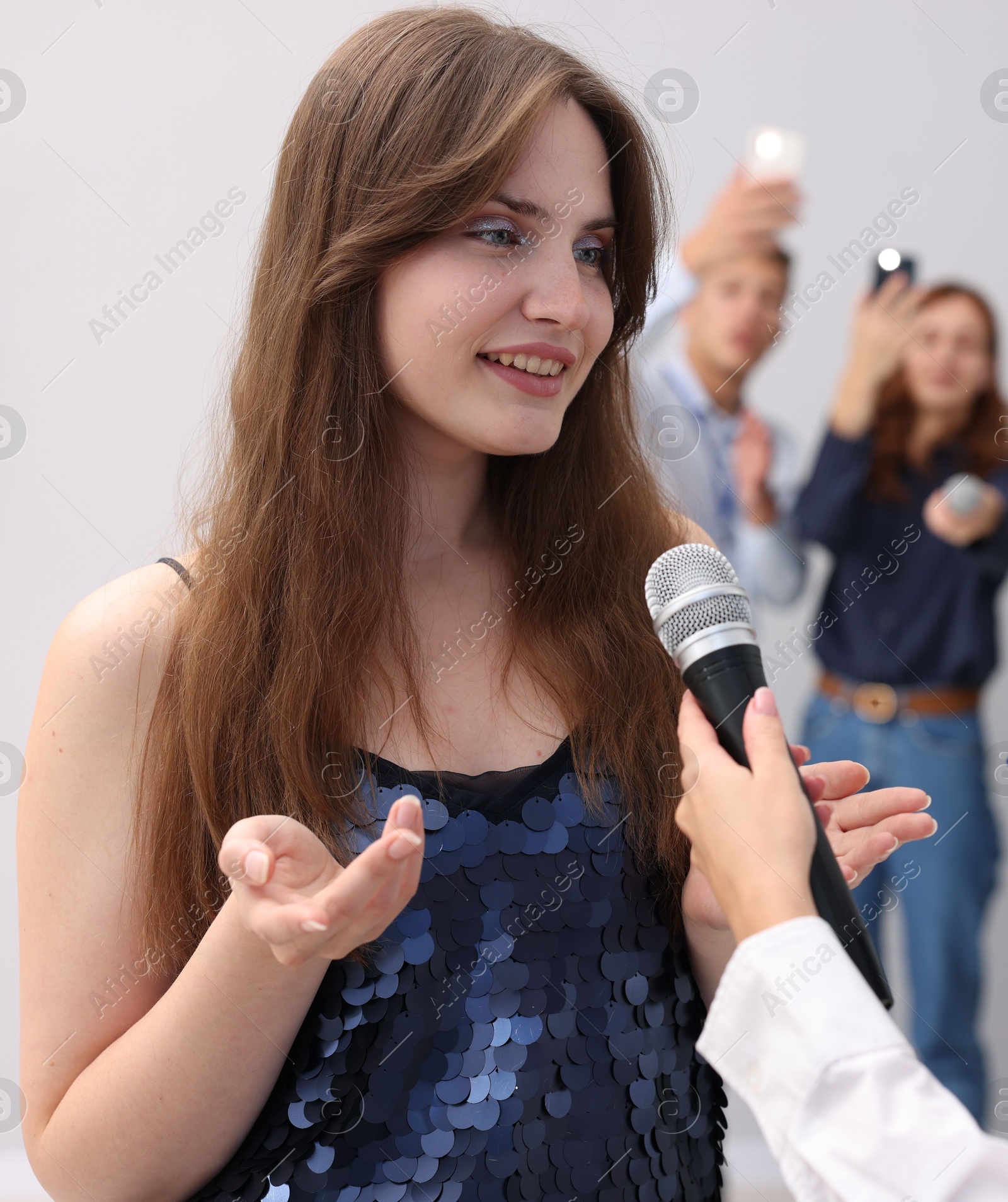 Photo of Beautiful woman giving interview to journalists on light background
