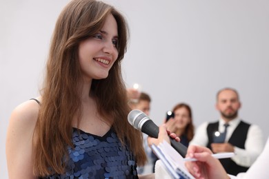 Photo of Beautiful woman giving interview to journalists on light background