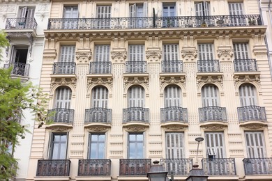 Photo of Beautiful building with windows and balconies in city, low angle view