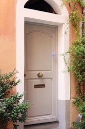 Photo of Entrance of residential house with beige door and beautiful green plants