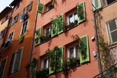 Photo of Facade of building with beautiful potted plants, low angle view