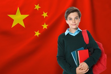 Image of Student with backpack and notebooks against flag of China. Language school