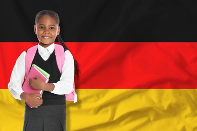 Image of Little girl with backpack and notebooks against flag of Germany. Language school