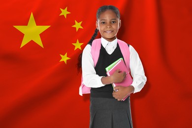 Image of Little girl with backpack and notebooks against flag of China. Language school