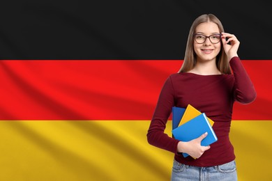 Image of Student with eyeglasses and notebooks against flag of Germany. Language school