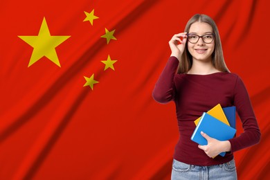 Image of Student with eyeglasses and notebooks against flag of China. Language school