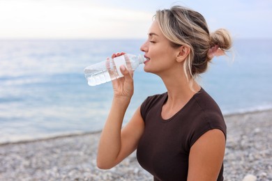 Photo of Beautiful young woman drinking water at beach