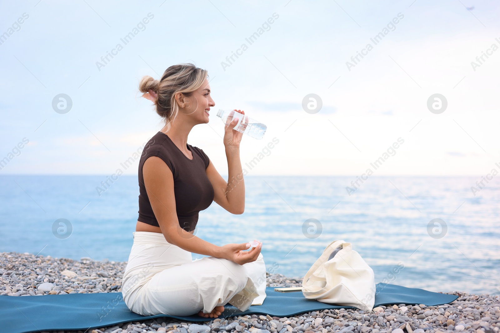 Photo of Beautiful young woman drinking water at beach