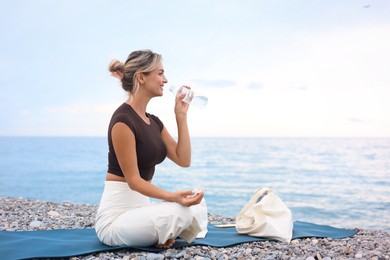 Photo of Beautiful young woman drinking water at beach