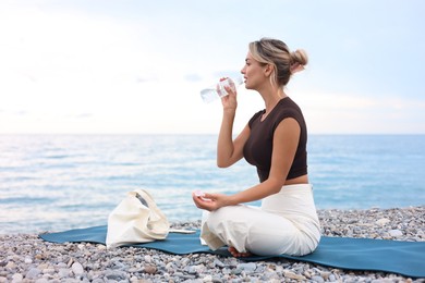 Photo of Beautiful young woman drinking water at beach
