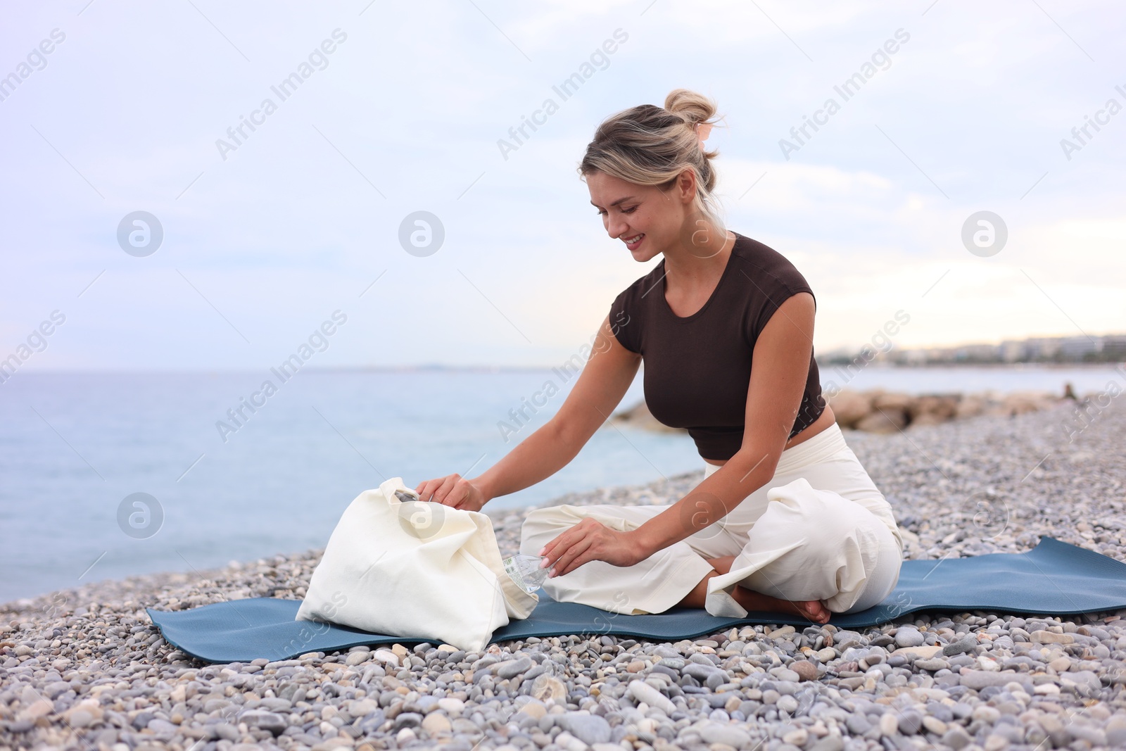 Photo of Beautiful young woman on yoga mat at beach