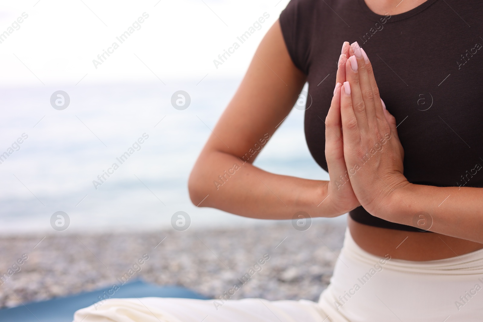 Photo of Young woman practicing yoga at beach, closeup. Space for text