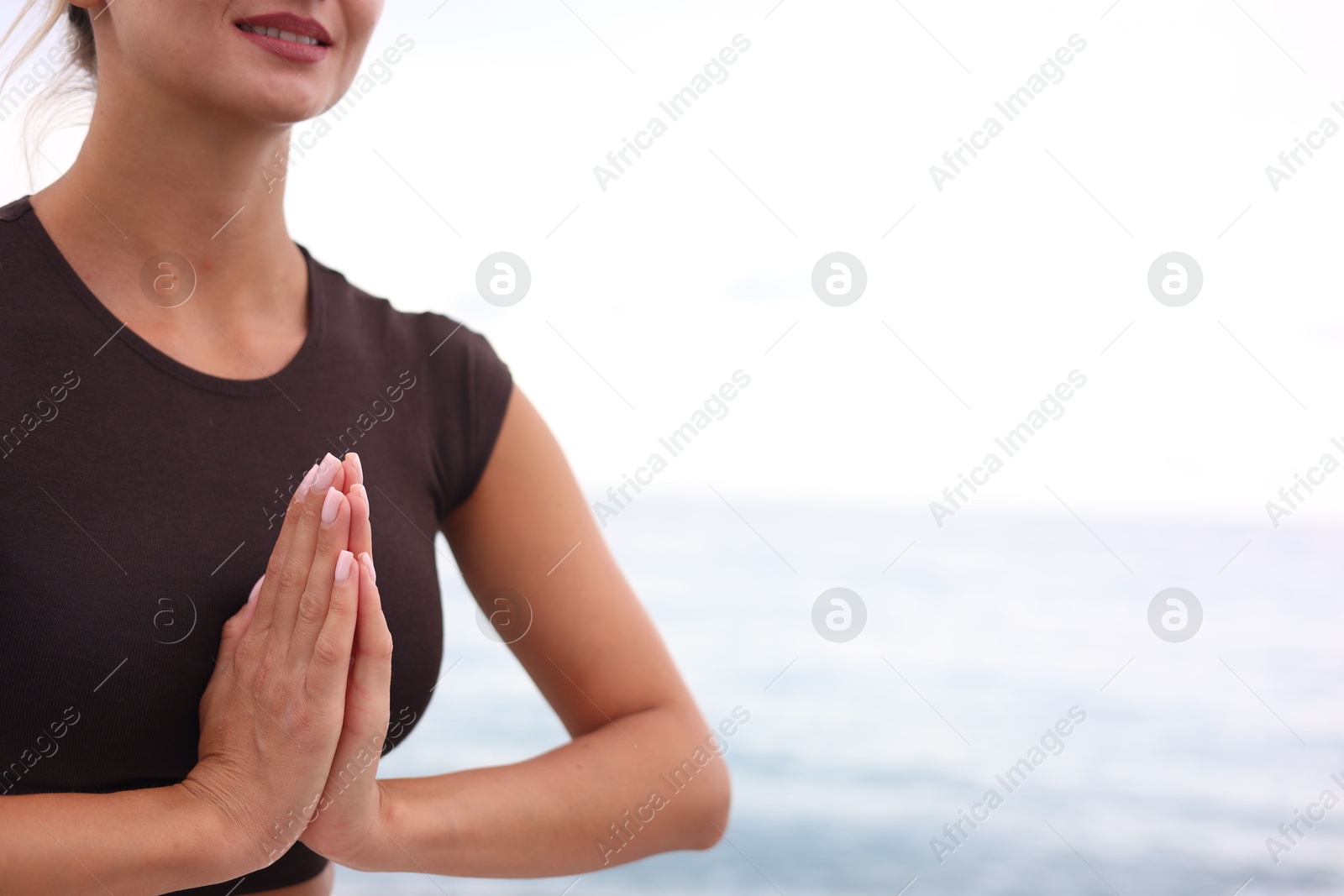Photo of Young woman practicing yoga at beach, closeup. Space for text