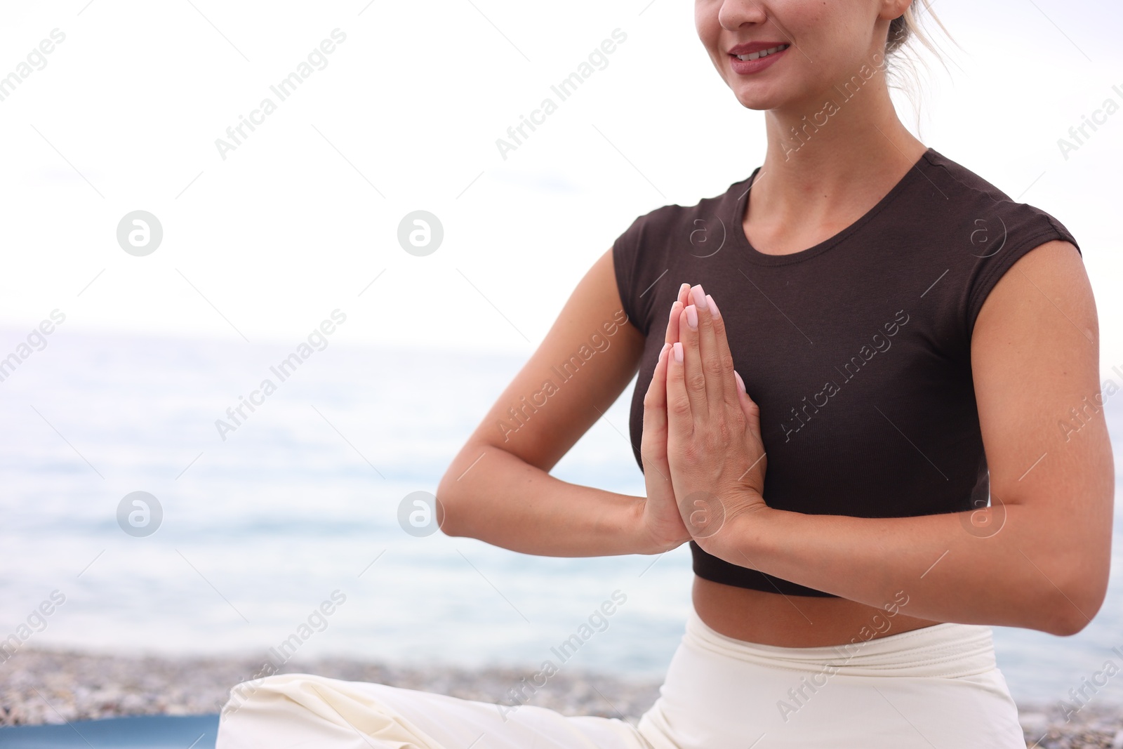 Photo of Young woman practicing yoga at beach, closeup. Space for text