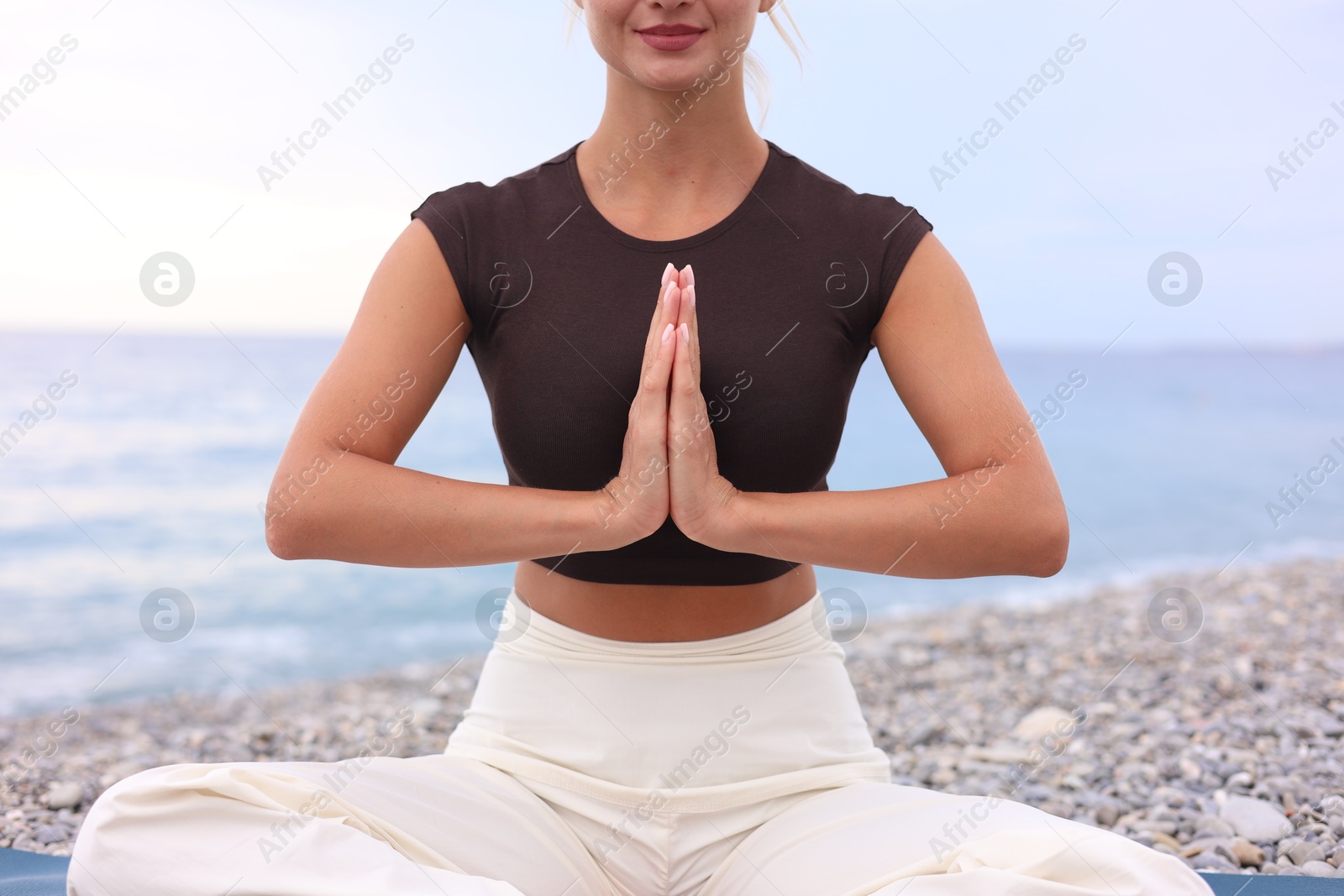Photo of Young woman practicing yoga at beach, closeup