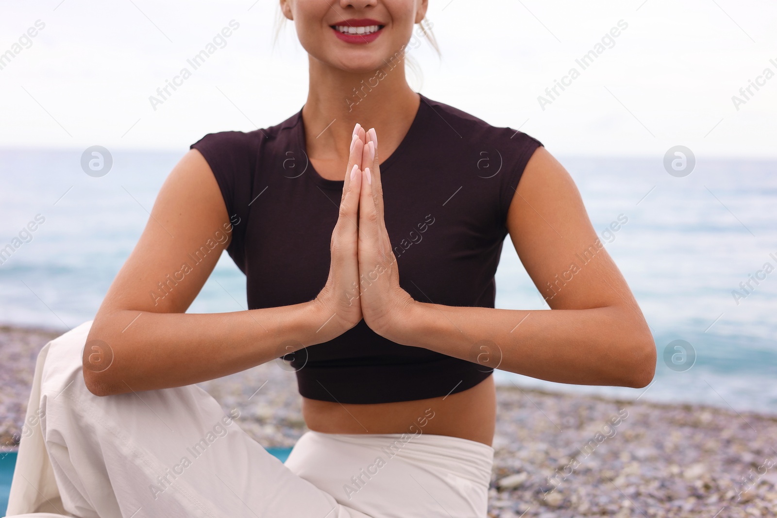 Photo of Young woman practicing yoga at beach, closeup