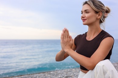 Photo of Young woman practicing yoga at beach, space for text