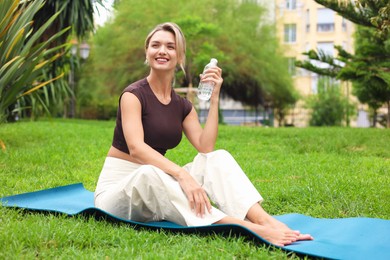 Photo of Young woman with bottle of water in park