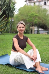 Photo of Young woman on yoga mat in park