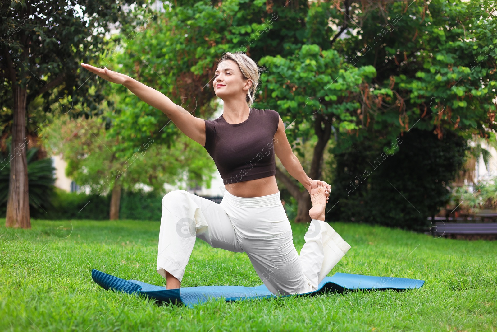 Photo of Young woman practicing yoga on mat in park
