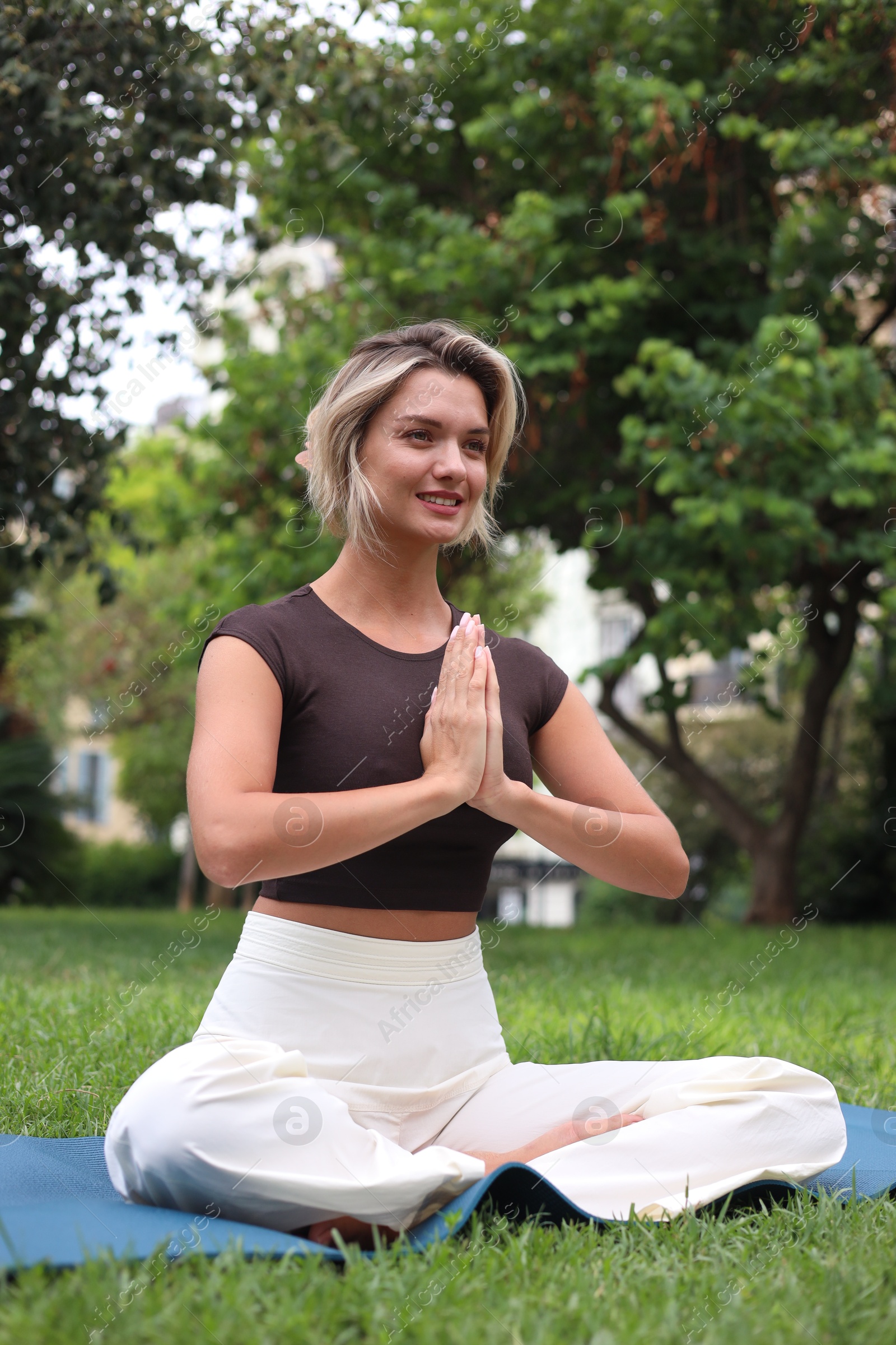 Photo of Young woman practicing yoga on mat in park