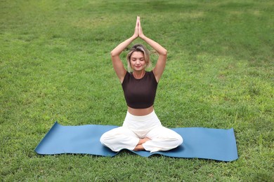 Photo of Young woman practicing yoga on mat in park