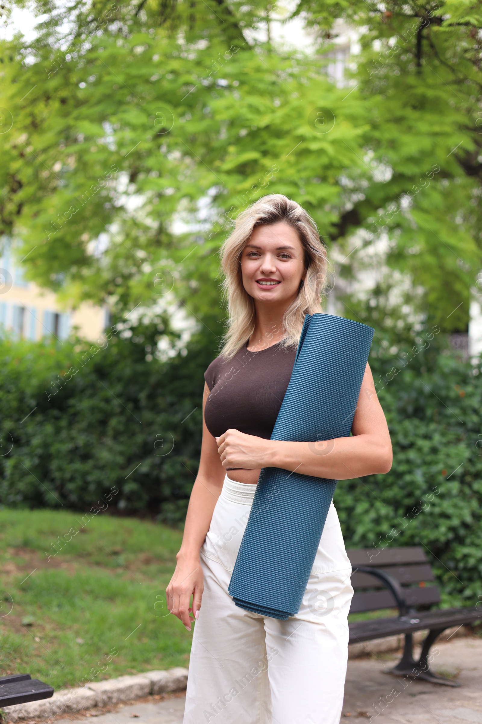 Photo of Beautiful young woman with yoga mat outdoors