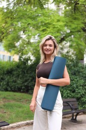 Photo of Beautiful young woman with yoga mat outdoors