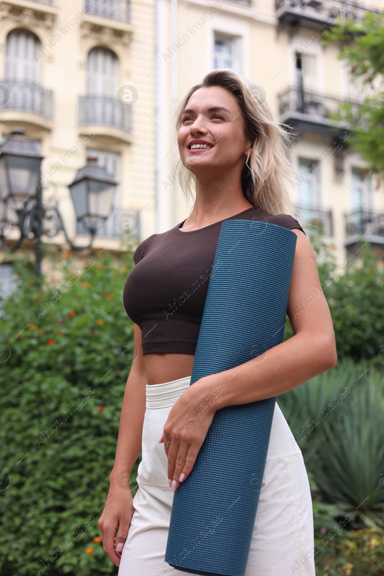 Photo of Beautiful young woman with yoga mat outdoors