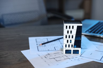 Photo of Real estate. Apartment building model, architectural drawings and laptop on table indoors, closeup. Space for text