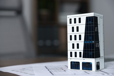 Photo of Real estate. Apartment building model and paperwork on table indoors, closeup. Space for text