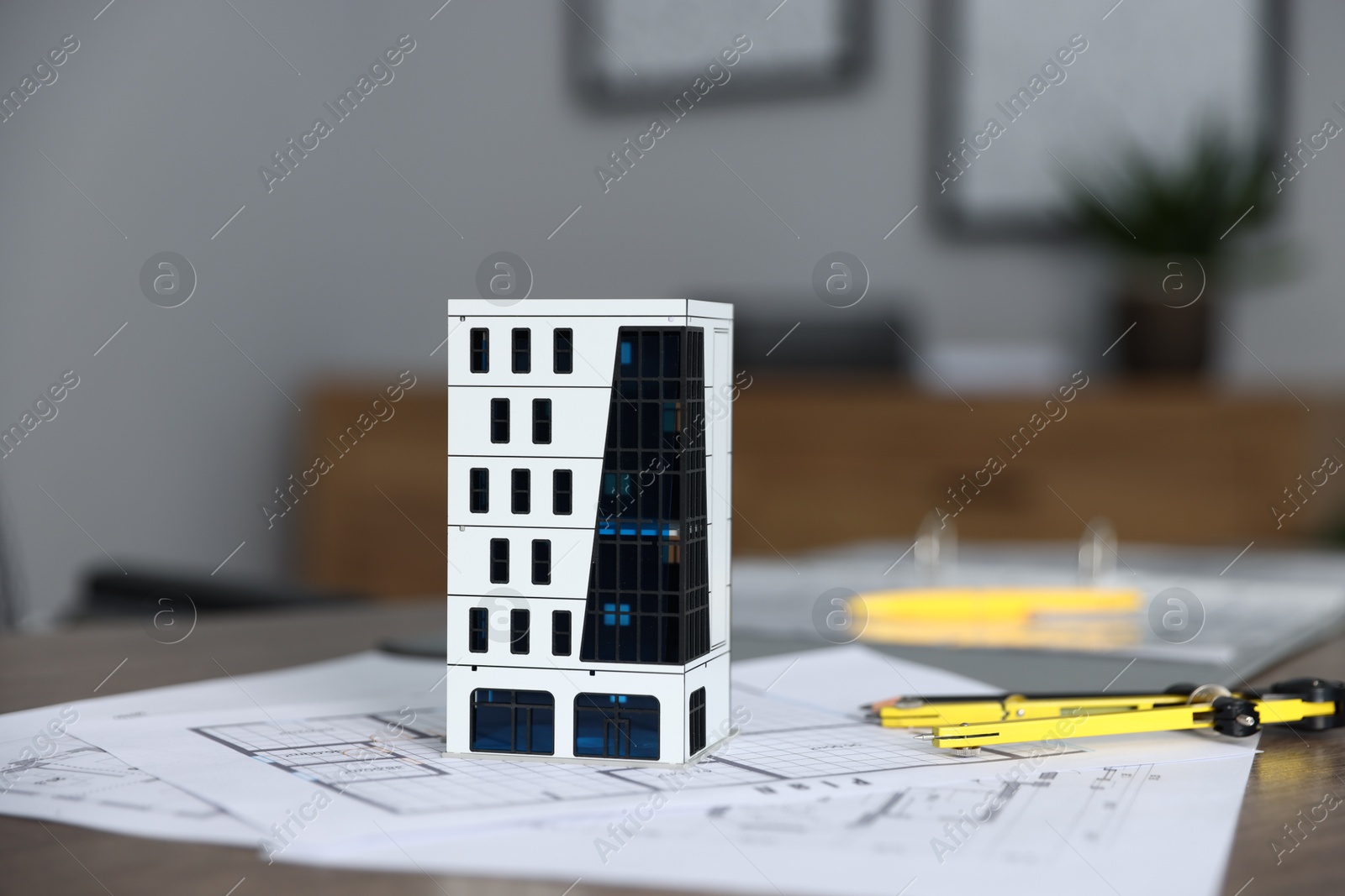 Photo of Real estate. Apartment building model and paperwork on table indoors, closeup