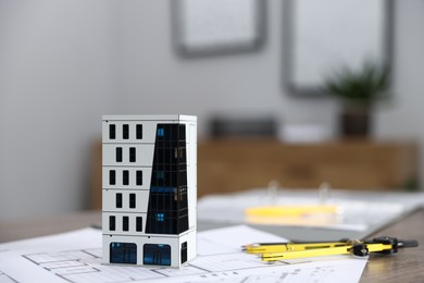 Photo of Real estate. Apartment building model and paperwork on table indoors, closeup. Space for text