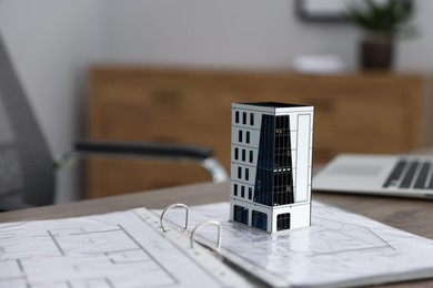 Photo of Real estate. Apartment building model, architectural drawings and laptop on table indoors, closeup. Space for text