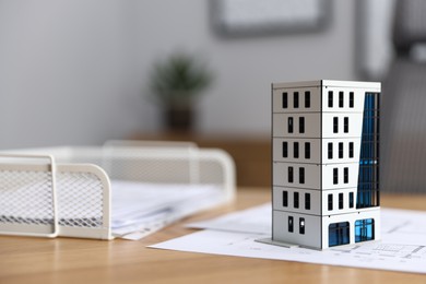 Photo of Real estate. Apartment building model and paperwork on table indoors, closeup. Space for text