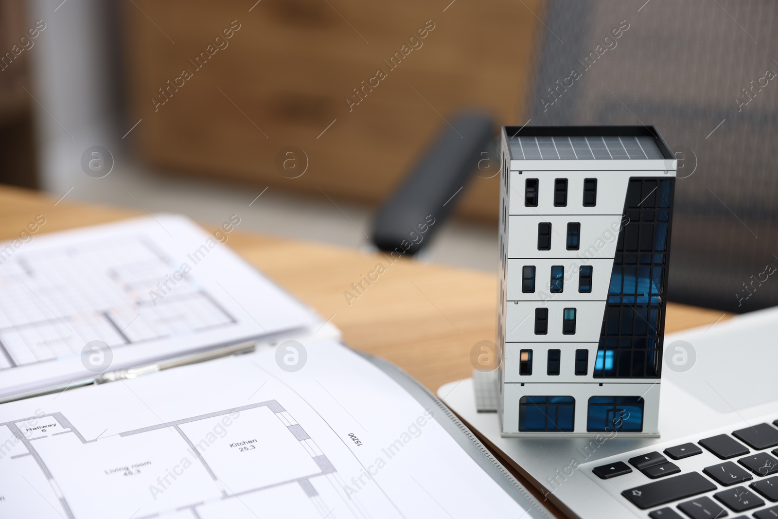 Photo of Real estate. Apartment building model, architectural drawings and laptop on table indoors, closeup. Space for text