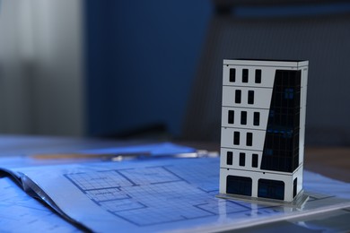 Photo of Real estate. Apartment building model and paperwork on table indoors, closeup. Space for text
