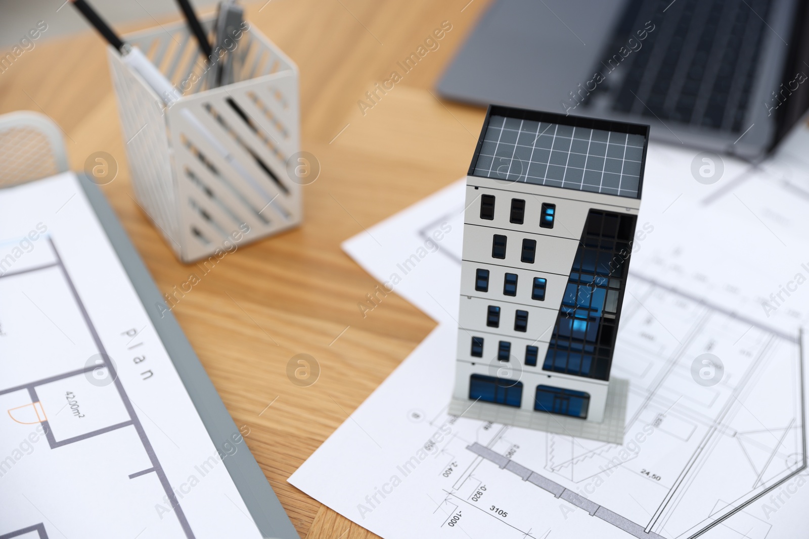 Real estate. Apartment building model, architectural drawings and laptop on table, closeup Photo of Real estate. Apartment building model, architectural drawings and laptop on table, closeup