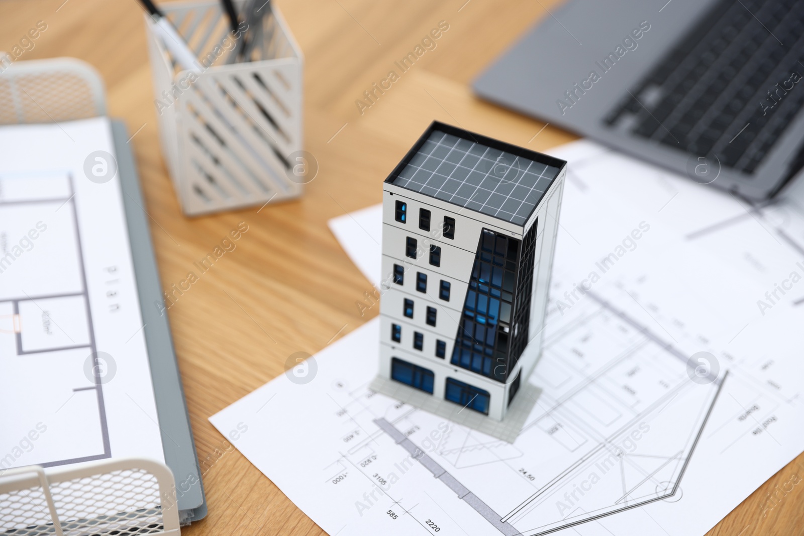 Photo of Real estate. Apartment building model, architectural drawings and laptop on table, closeup