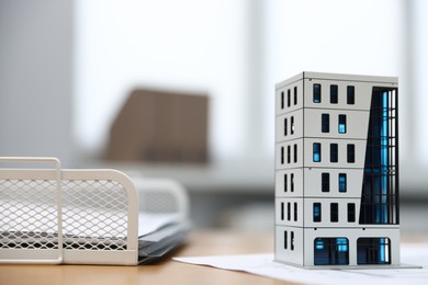 Photo of Real estate. Apartment building model on wooden table indoors, closeup. Space for text