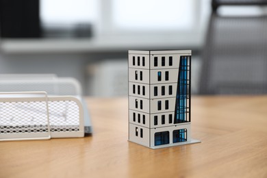 Photo of Real estate. Apartment building model on wooden table indoors, closeup