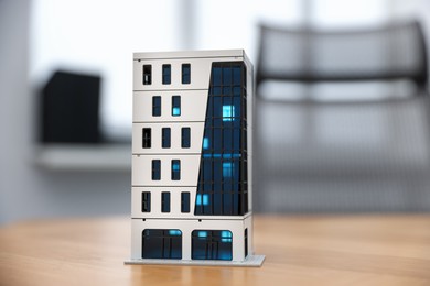 Photo of Real estate. Apartment building model on wooden table indoors, closeup