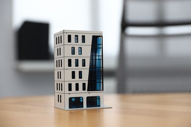 Photo of Real estate. Apartment building model on wooden table indoors, closeup. Space for text
