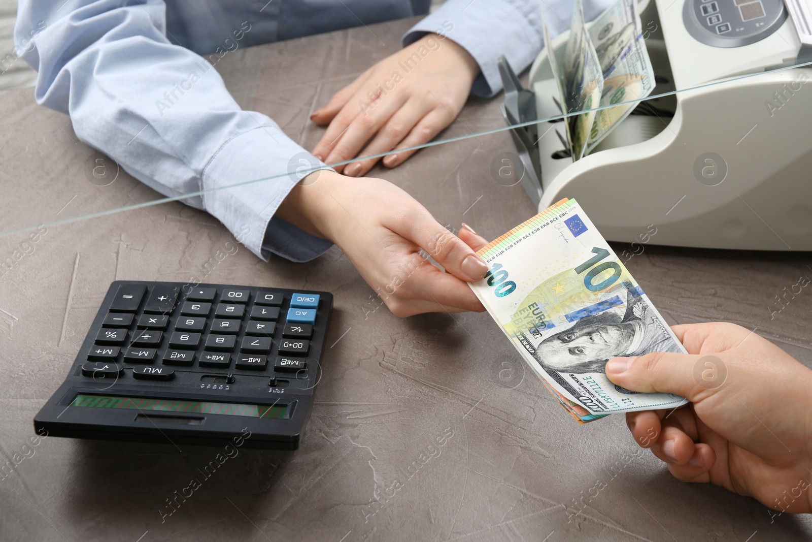 Image of Money exchange. Client giving banknotes to cashier at table, closeup. Bill changing from dollar to euro
