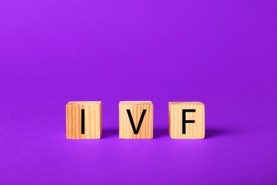 Image of In vitro fertilization. Wooden cubes with abbreviation IVF on purple background